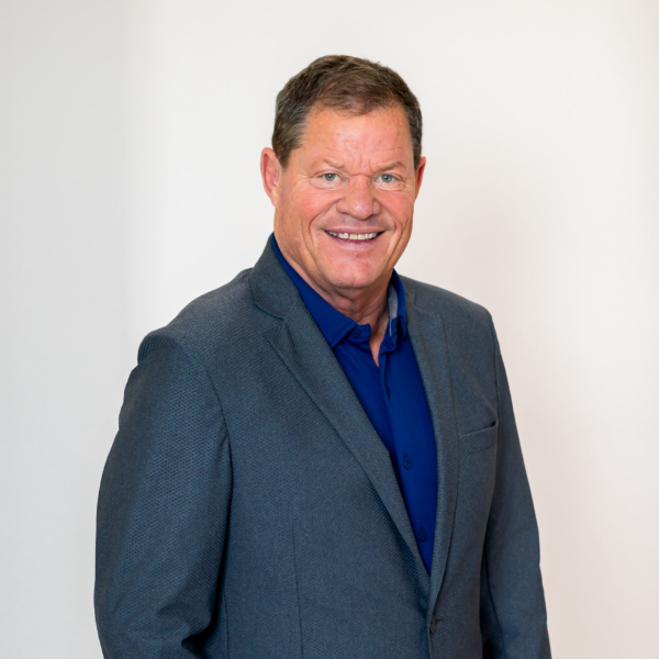 Bob David, co-founder of Leadership Properties, smiling in a professional setting, wearing a blazer and collared shirt, representing community development in Northwest Arkansas.